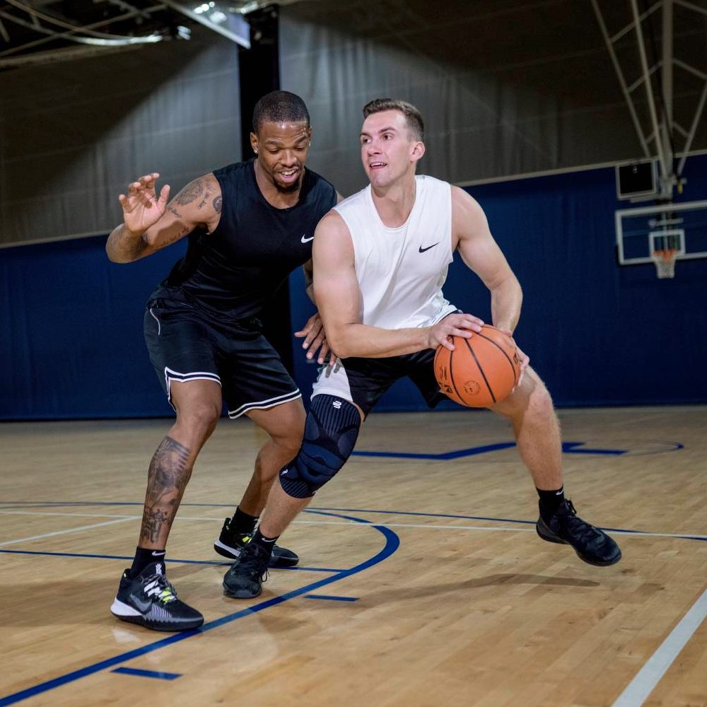 Two basketball players in a competitive game on an indoor court