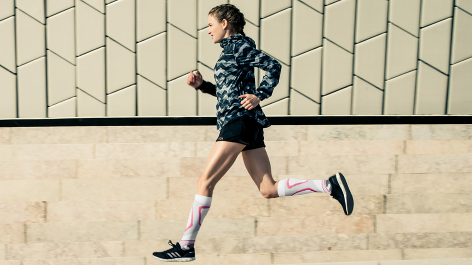 Woman wearing Bauerfeind's Run Performance Compression Socks while running through a city street.