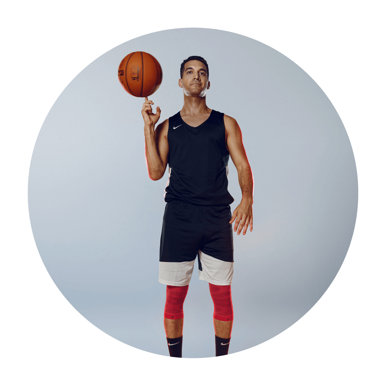 Athlete spinning a basketball on his index finger while in athlete clothing and wearing Bauerfeind's Sports Compression Knee Support NBA Bulls Edition.