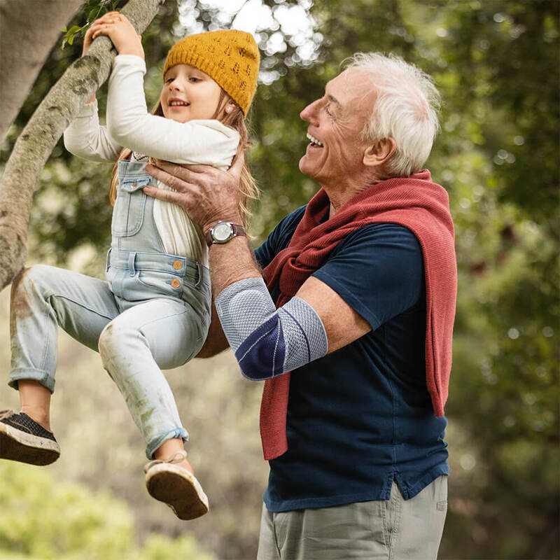 Image of a Grandfather wearing Bauerfeind's EpiTrain elbow brace while playing outside with his Granddaughter.