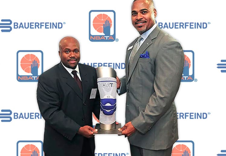 Two men in suits holding an award at the Bauerfeind and NBATA event