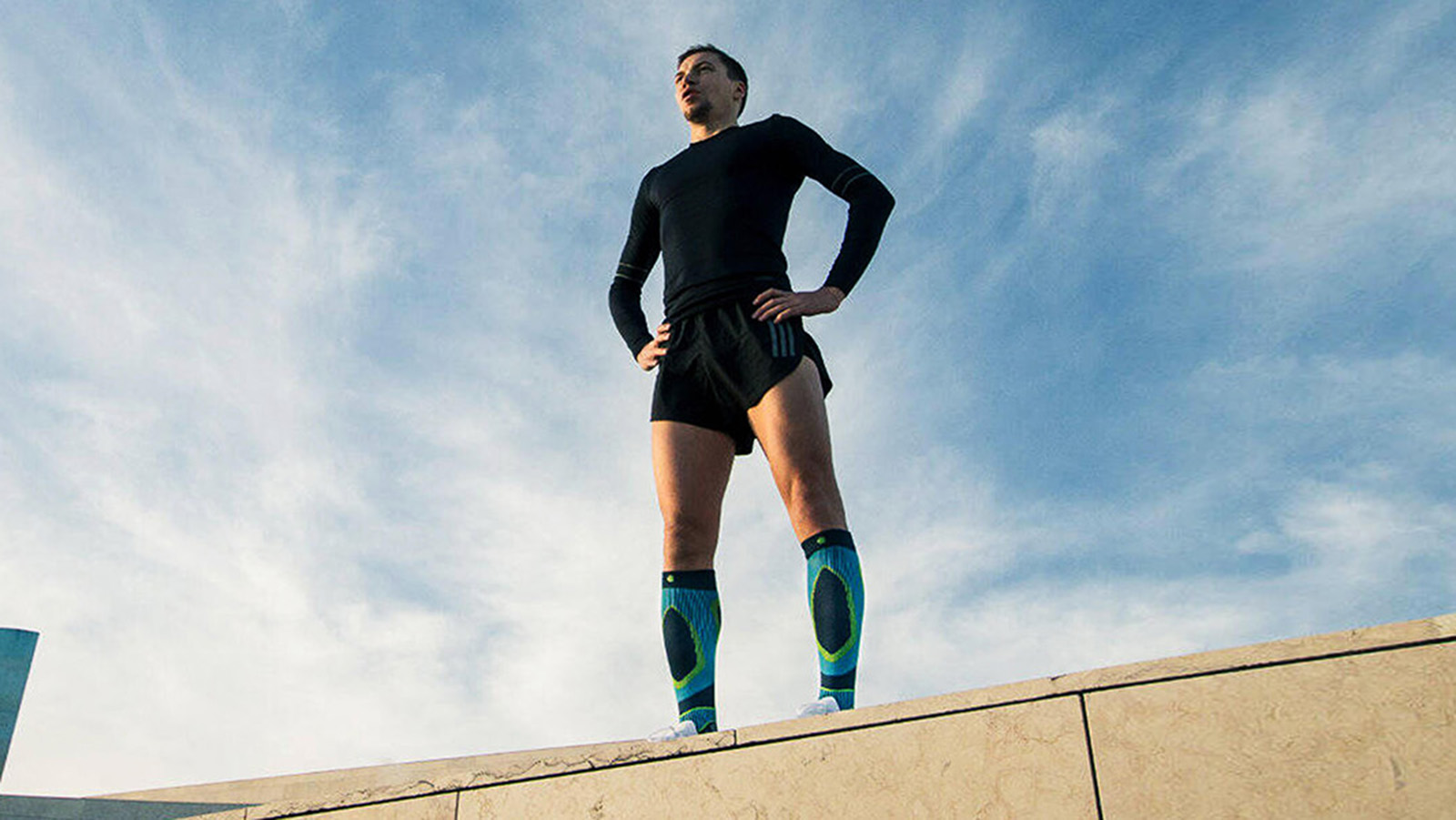 Man overlooking a city before a morning run while wearing Bauerfeind's Run Performance Compression Socks.