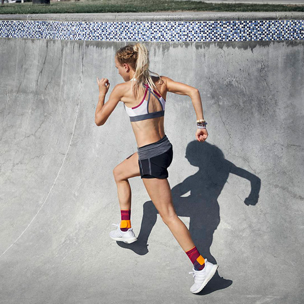 Woman running outside on cement while wearing Bauerfeind's Sports Ankle Support.