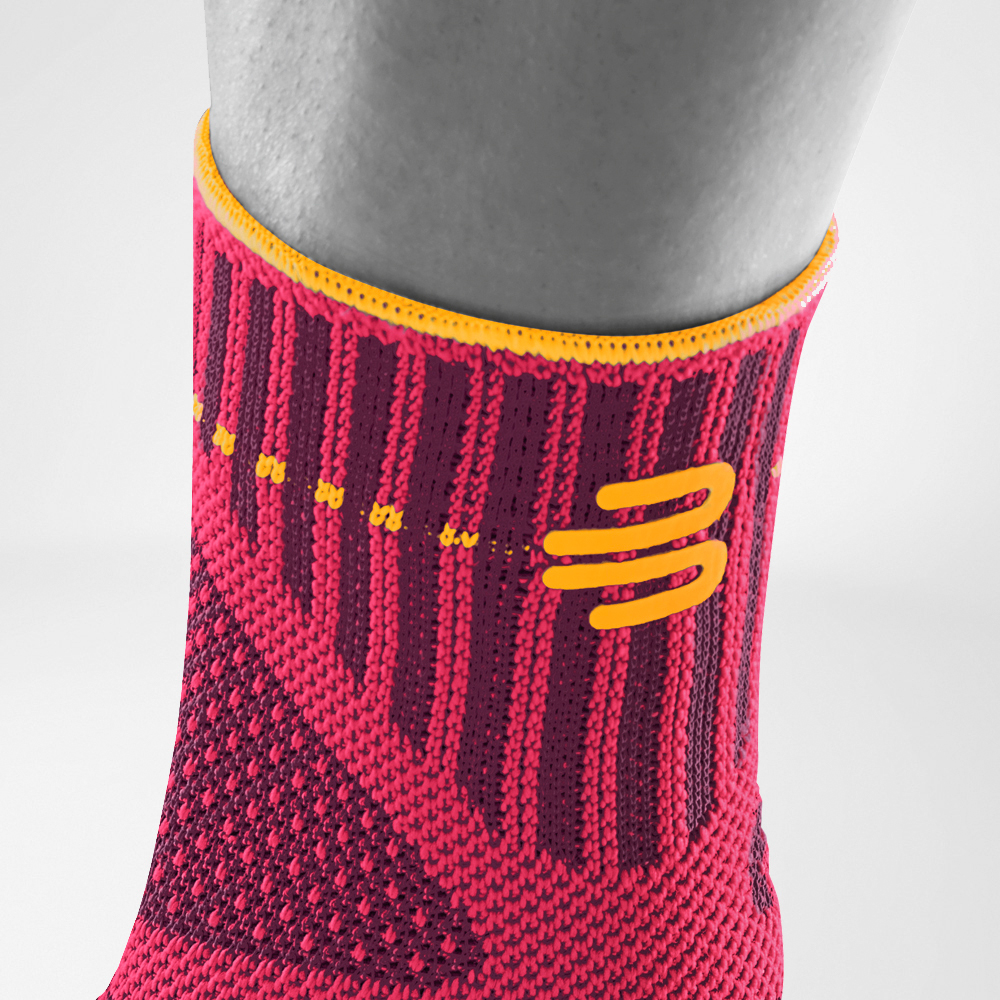 Close-up of an ankle wearing a red and orange compression sleeve for ankle support.