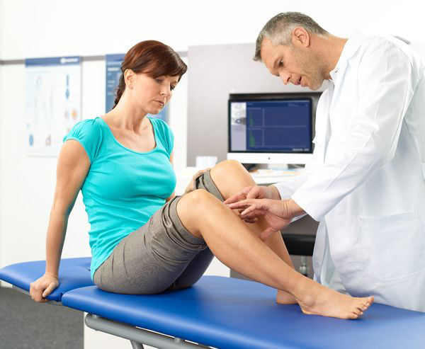 Physical therapist examining woman's knee.