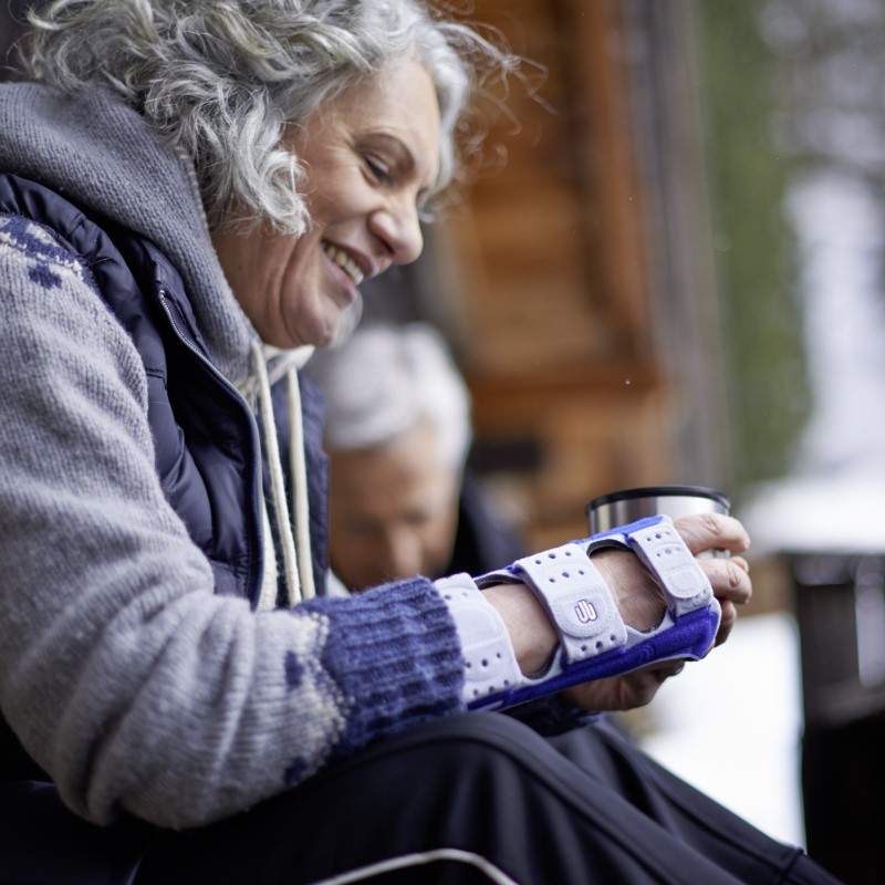 Image of a woman wearing Bauerfeind's ManuLoc wrist support splint while drinking coffee with husband on a winter morning.