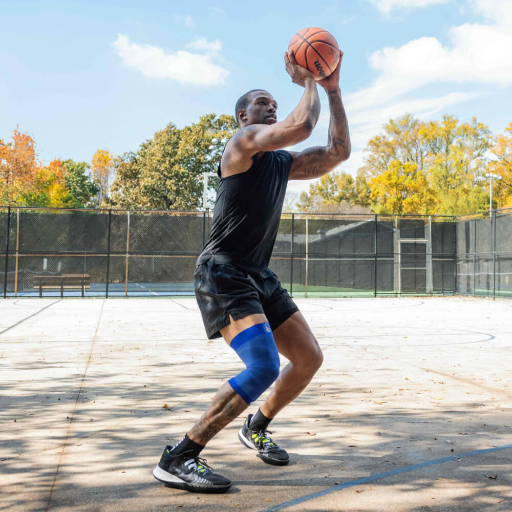 Man playing basketball outdoors, preparing to shoot a jump shot on a sunny day.