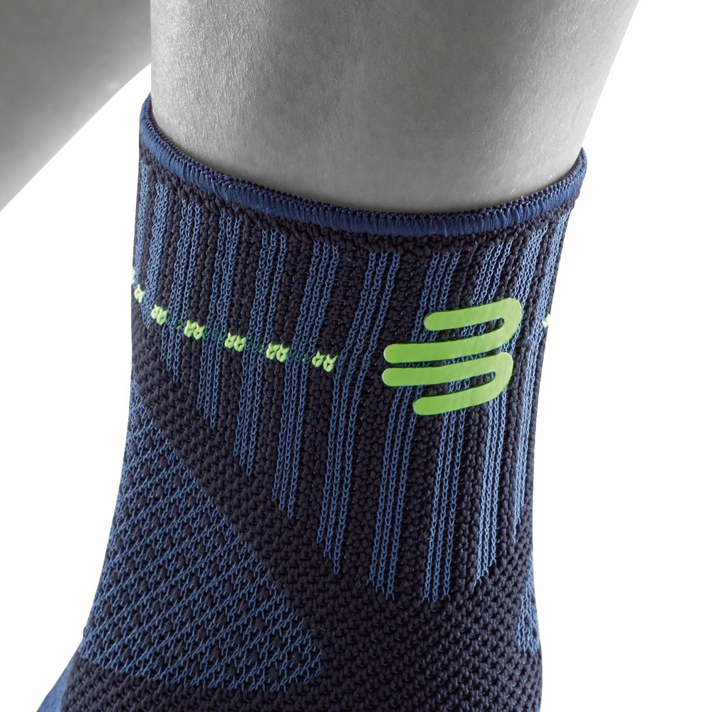 Close-up of a blue and black athletic compression sock with green accents around a person's lower leg.