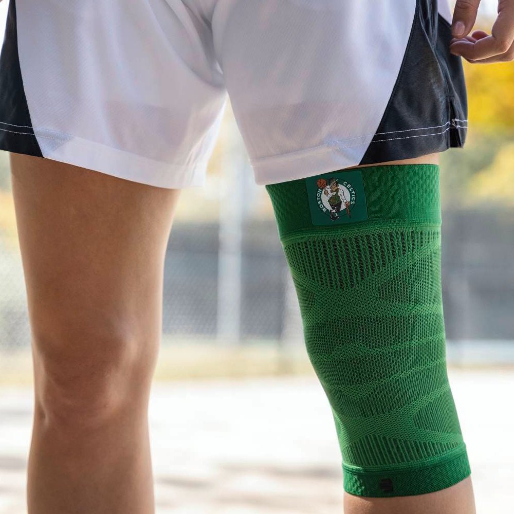 Person wearing a green Boston Celtics knee sleeve playing basketball