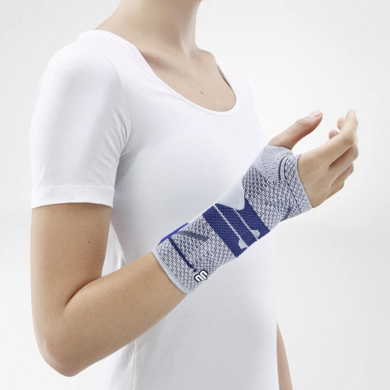 Image of the side of Bauerfeind's ManuTrain wrist brace while being worn by a person in front of a gray background.