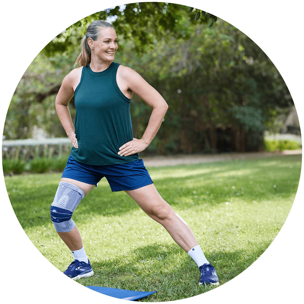 Woman walking along a trail while wearing Bauerfeind's GenuTrain knee brace.