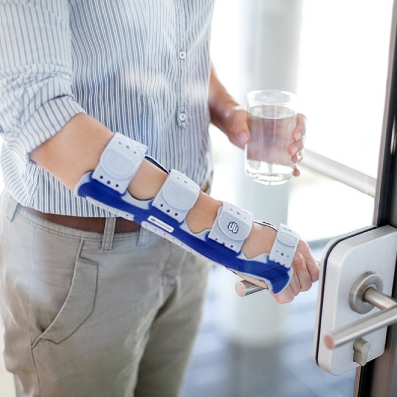 Image of a business man wearing Bauerfeind's ManuLoc long wrist brace while opening an office door.