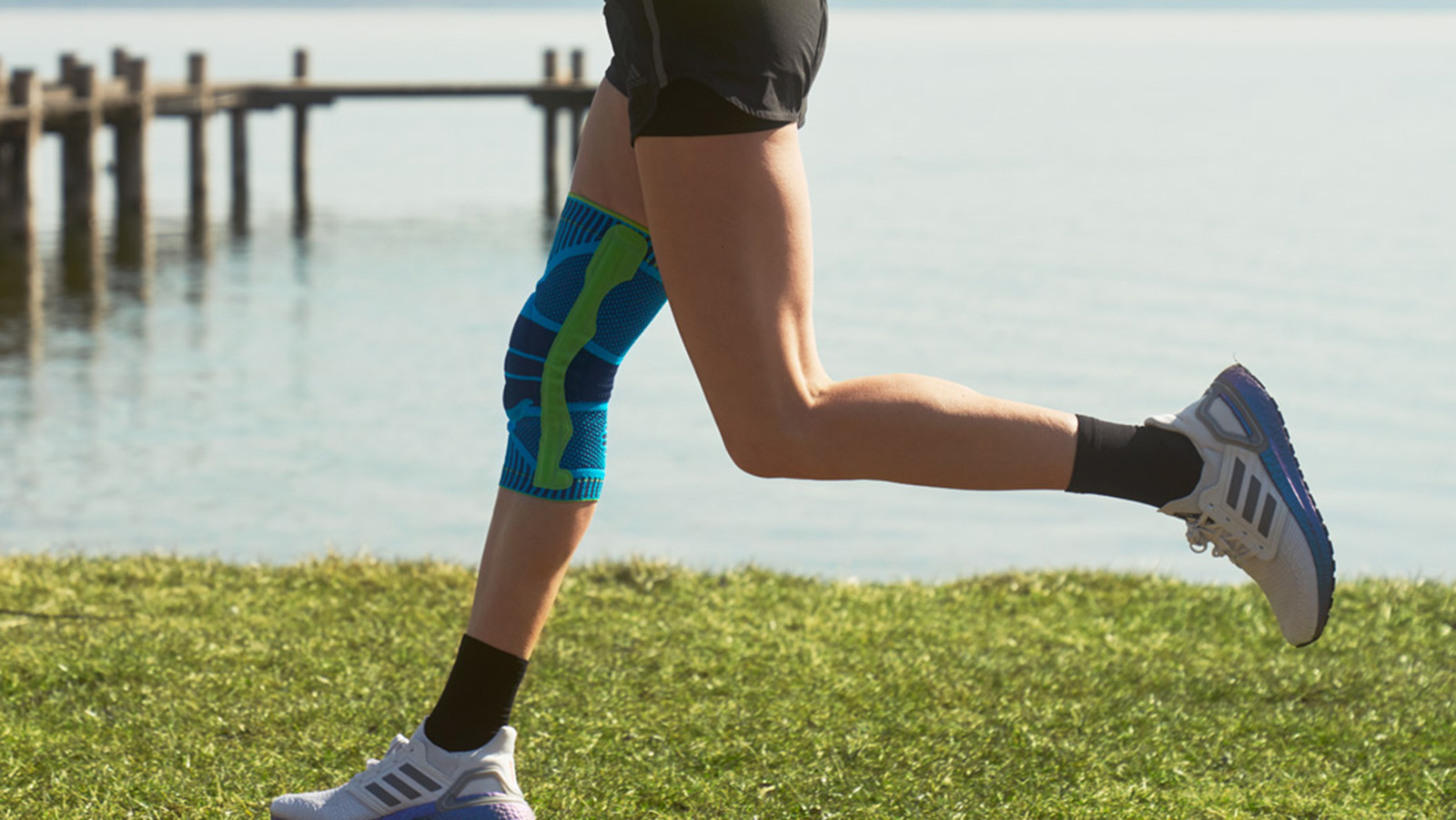 Woman running on a dock surrounded by a lake.