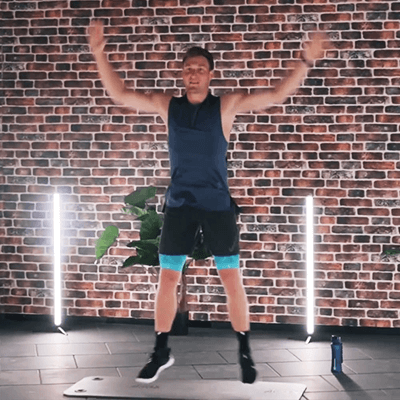 Olympic Gold Medalist Thomas Röhler performing jumping jacks inside of a fitness studio while wearing Bauerfeind's Sports Compression Upper Leg Sleeves.