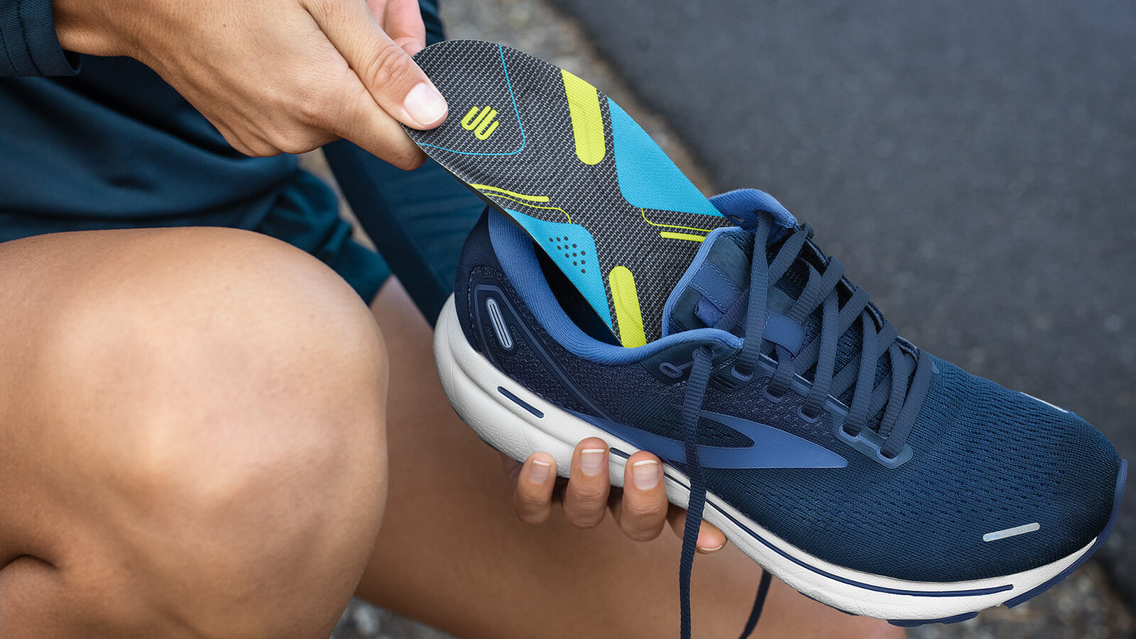 Person inserting Bauerfeind's Run Performance Insoles into their running shoes to enhance wearing comfort.