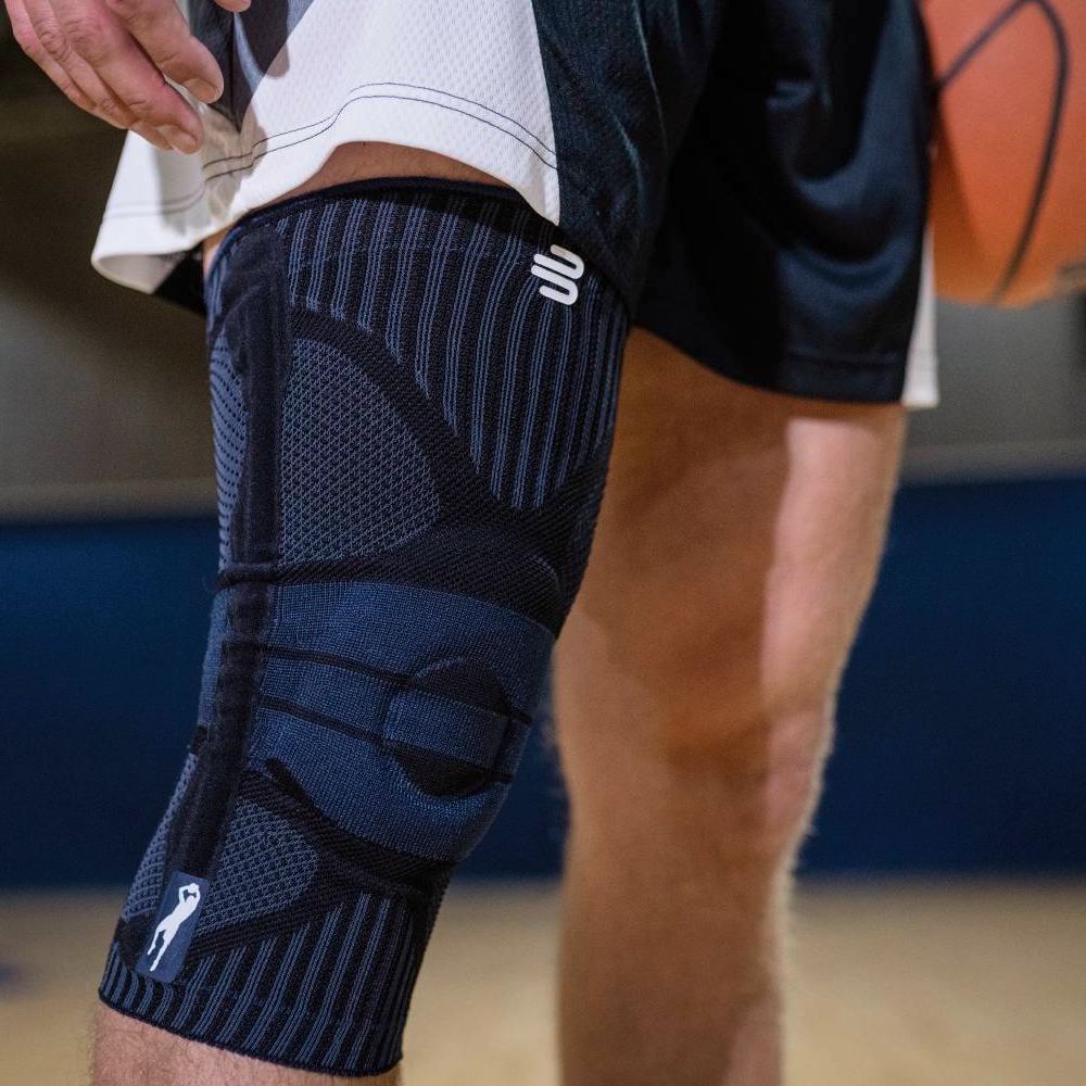 Close-up of a basketball player wearing a black knee support brace on the court.