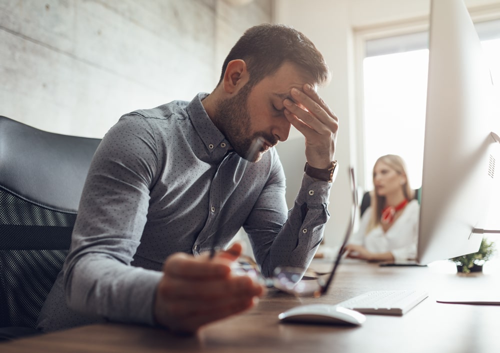 Person experiencing stress while sitting at office desk.